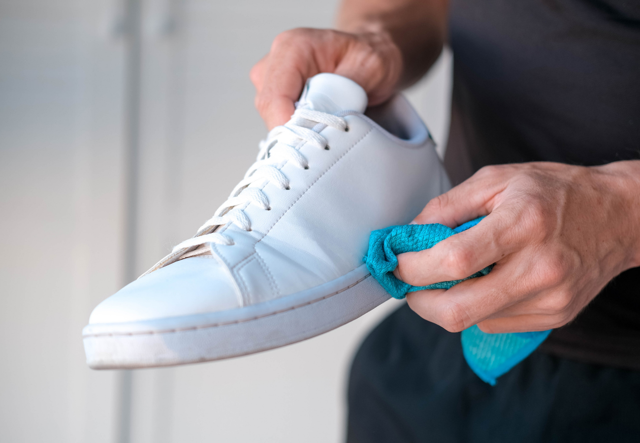Fresh mark being wiped from a white leather sneaker with a microfiber cloth
